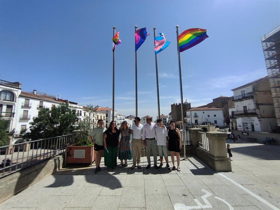 El alcalde de Cáceres, Rafael Mateos; la concejala de LGBTI, Jacobi Ceballos, y representantes de asociaciones izan las banderas LGBTIQ+ en la fachada del Ayuntamiento de Cáceres