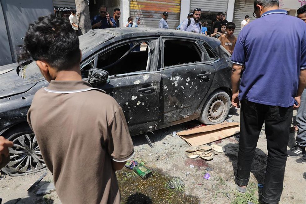 Palestinos alrededor de un vehículo atacado por Israel en ciudad de Gaza