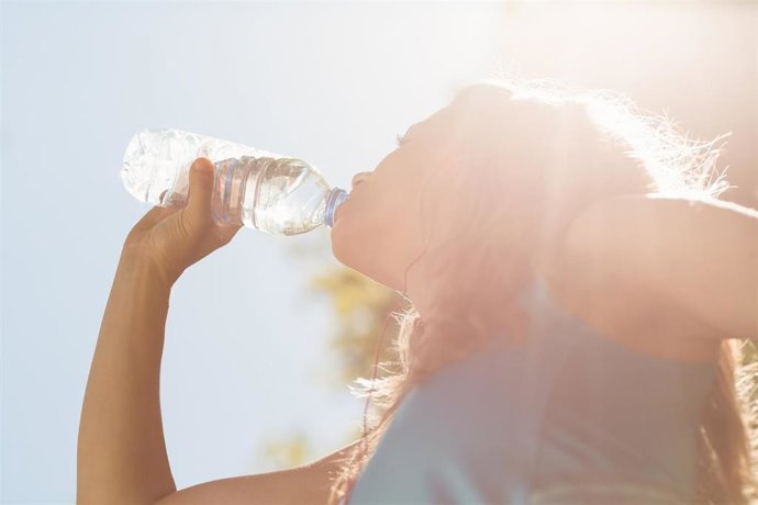 Archivo - Una chica bebe agua de una botella bajo el sol.