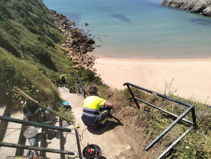 Personal de Piélagos repara la barandilla de acceso a la playa de Somocuevas tras la autorización de Costas