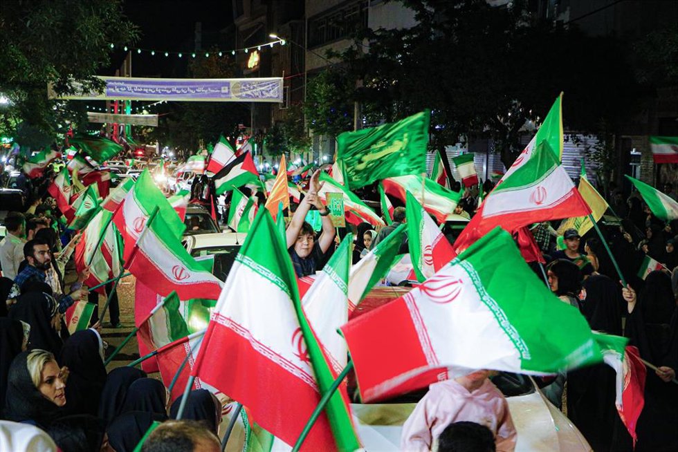 Una multitud agita banderas iraníes a lo largo de una calle durante una manifestación organizada por el Estado en Irán.
