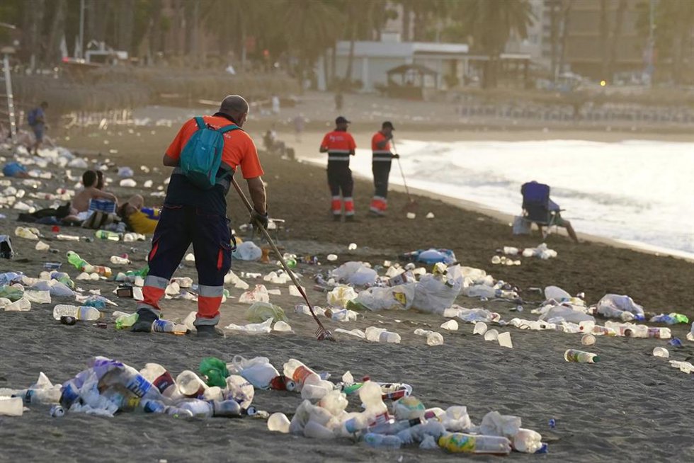 Operarios del servicio de limpieza municipal de Málaga trabajan en la retirada de basura en la playa de La Malagueta tras la celebración de la noche de San Juan.