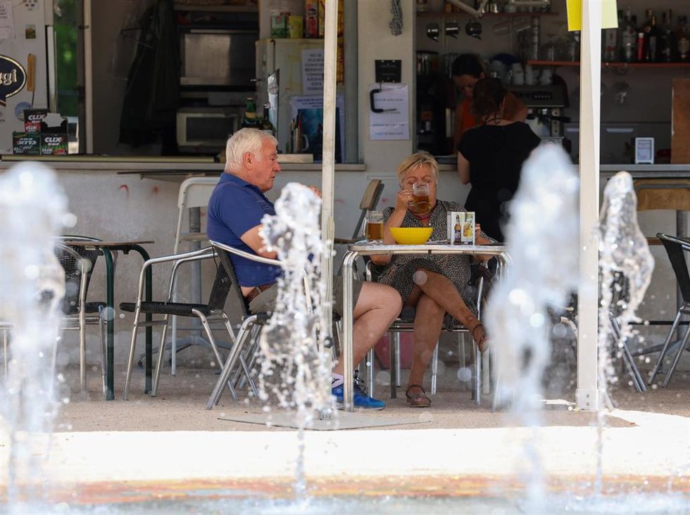 Archivo - Varias personas tratan de refrescarse en la terraza de un bar durante una ola de calor.
