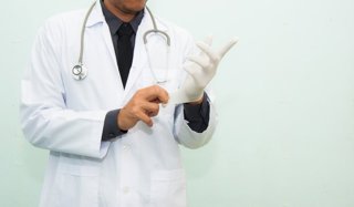 Archivo - Un médico poniéndose un guante.