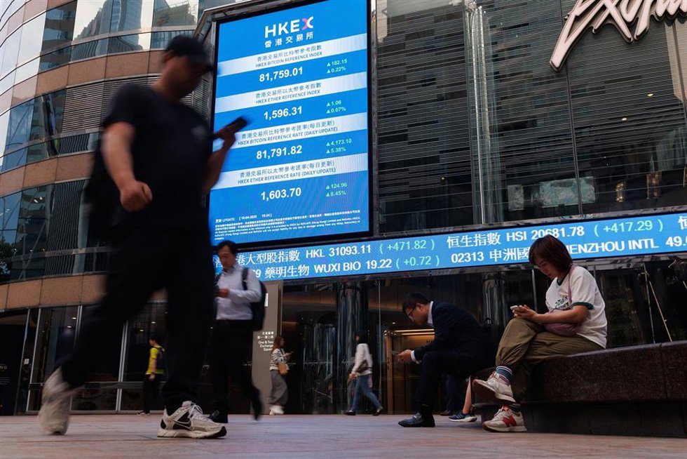 Archivo - 10 April 2025, China, Hongkong: People look at their phone under an electronic board showing the price of the Hang Seng Index at Hang Seng Bank headquarters in Hong Kong. Photo: May James/ZUMA Press Wire/dpa