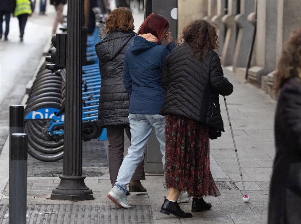 Archivo - Una persona con discapacidad visual camina acompañada por la calle.