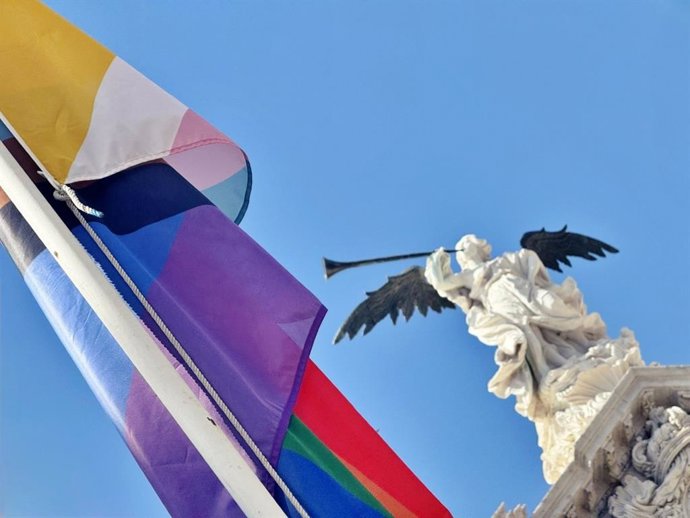 La bandera LGTBIQA+ ondea junto a la fachada del Rectorado de la Universidad de Sevilla, con la escultura de la Fama, al fondo