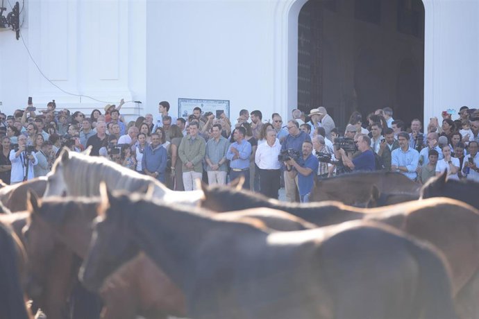 El presidente en funciones de la Junta de Andalucía, Juanma Moreno (al fondo, en la puerta de la ermita con camisa gris), asiste a la Saca de las Yeguas de Almonte.