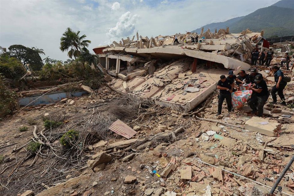 25 June 2026, Venezuela, La Guaira: Rescue workers carry a person out of the rubble of a house, that was affected by the earthquake that hit Venezuela. Just under a day after the disaster, at least 200 people are still officially trapped under the rubble,