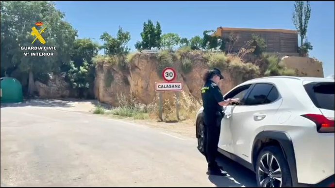 Una agente de la Guardia Civil controla el acceso a la localidad de Calasanz, a cuyos vecinos se les ha permitido el regreso este sábado tras la evacuación por el incendio de Tamarite