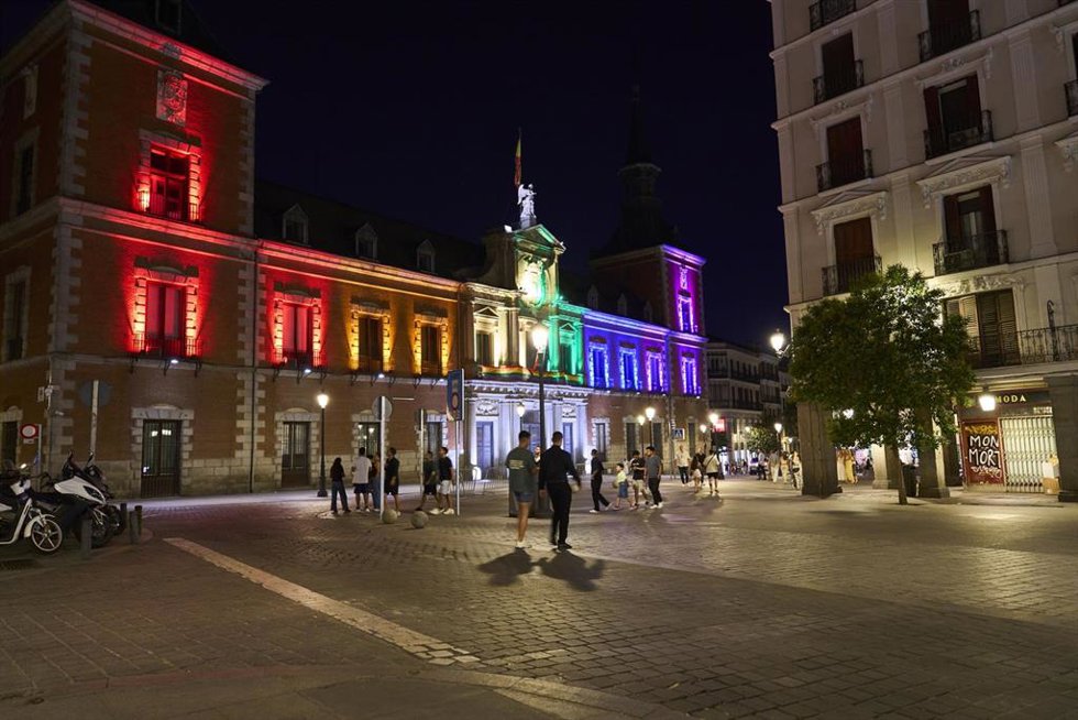 Fachadas de los edificios del MAEC en Marqués de Salamanca y Santa Cruz con la bandera del orgullo LGTBI e iluminación nocturna.