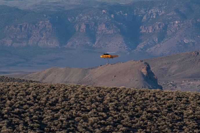 25 de junho de 2026, Junction, Utah, EUA: Um helicóptero de combate a incêndios sobrevoa a paisagem montanhosa próxima ao Reservatório Piute enquanto atende ao incêndio florestal de Cottonwood, que avança rapidamente. O incêndio florestal teve início a ci