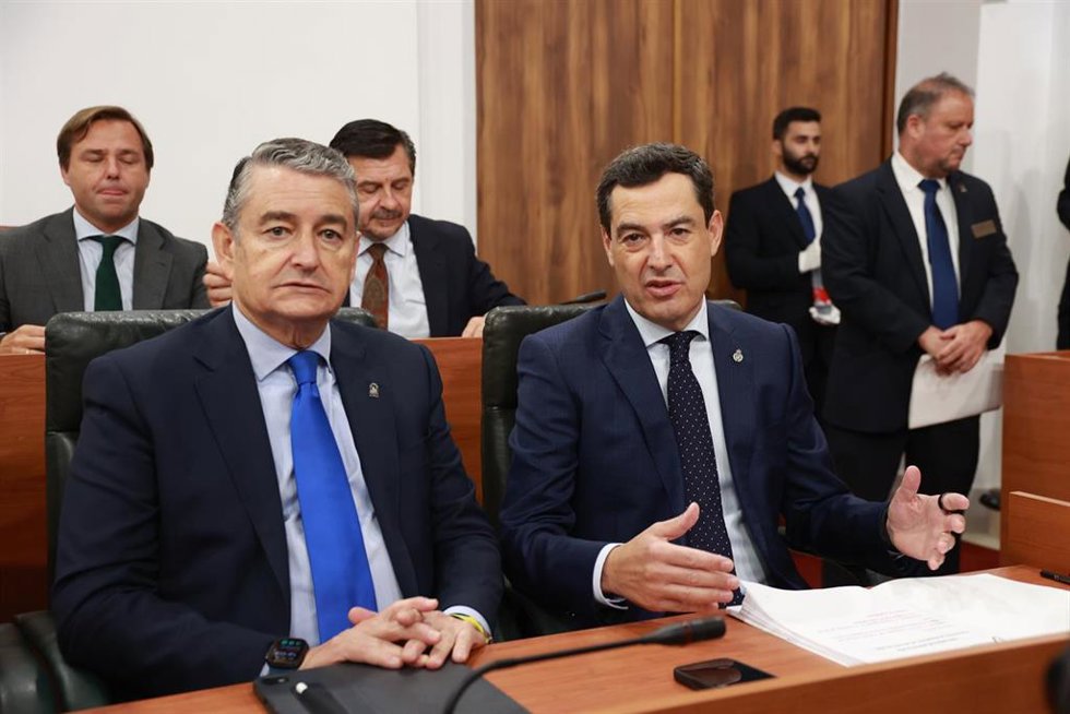 El presidente en funciones de la Junta y candidato del PP a la reelección, Juanma Moreno (d), junto al consejero en funciones de Sanidad, Presidencia y Emergencias, Antonio Sanz (i), ocupa su escaño antes de intervenir en el debate de investidura que acog