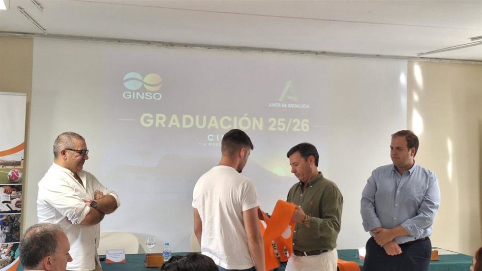 El subdelegado de la Junta en el Campo de Gibraltar, Javier Ros, poniendo la banda de graduación a uno de los menores infractores que cursa sus estudios en el Centro de Internamiento de Menores Infractores (CIMI) La Marchenilla en Algeciras (Cádiz)