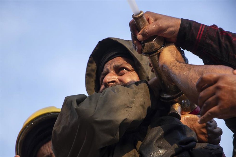 Archivo - Un bombero de India apunta con una manguera en funcionamiento