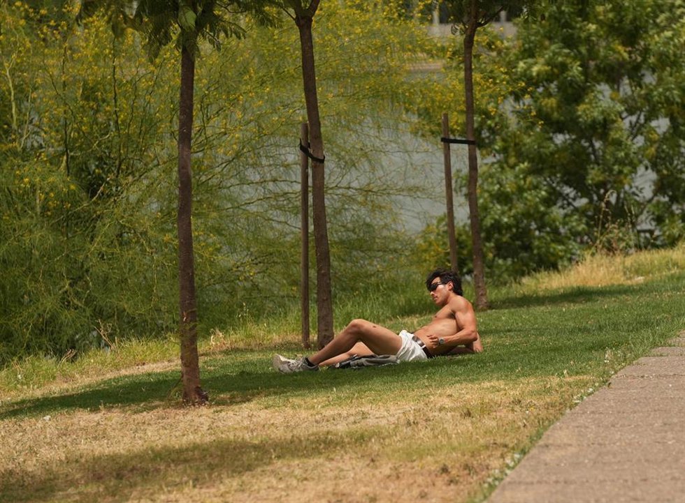 Una persona descansa junto al río. A 23 de junio de 2026, en Sevilla (Andalucía, España). 