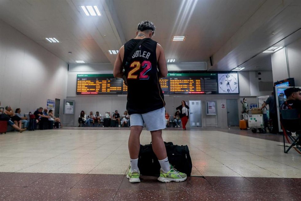 Archivo - Un joven junto a su maleta frente al panel de salidas en la estación de tren de Chamartín