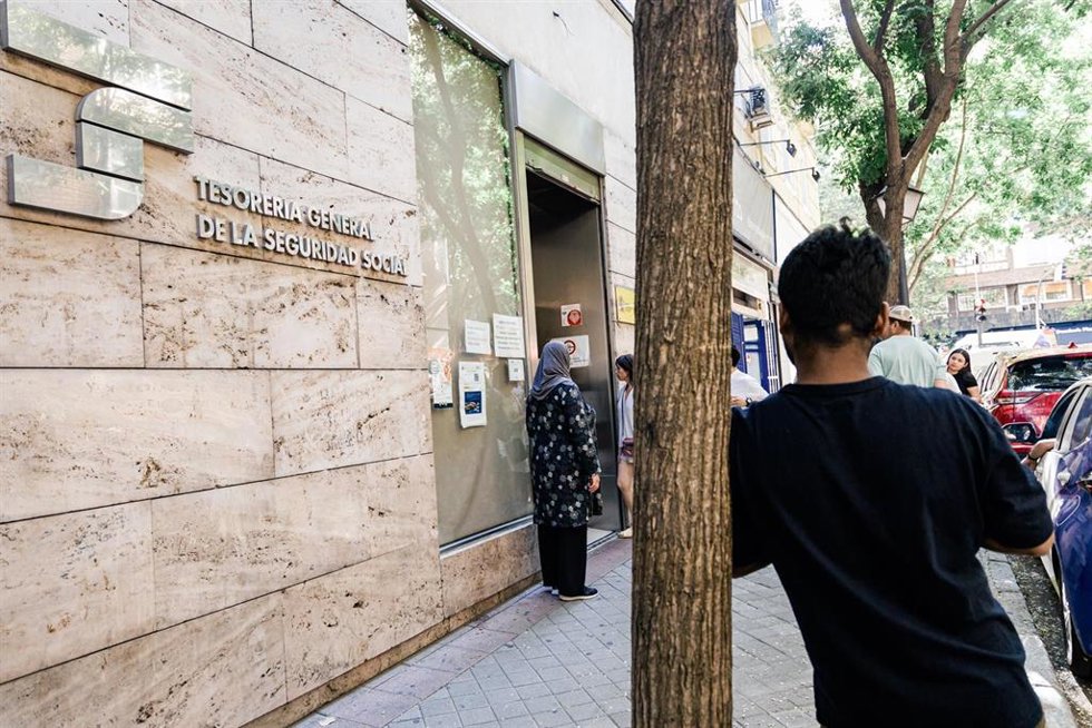 Varias personas migrantes esperan en el exterior de una oficina de la Seguridad Social, a 30 de junio de 2026, en Madrid (España). 