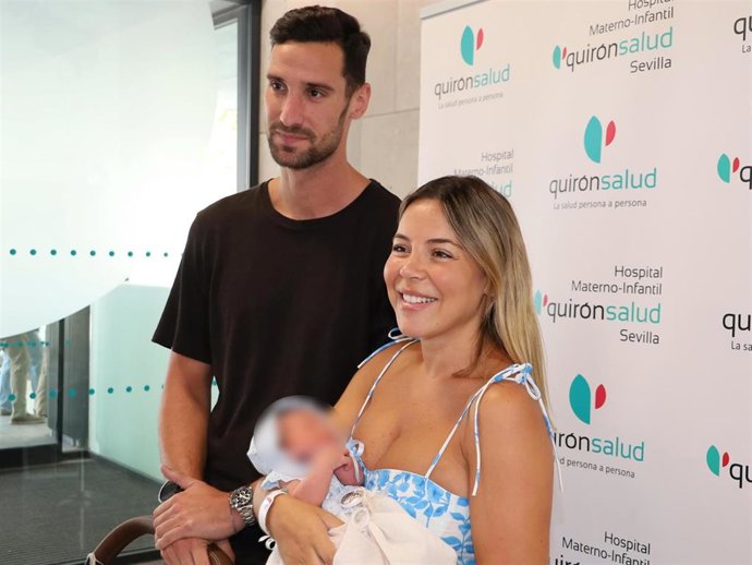 Sergio Rico y Alba Silva posando a las puertas del hospital con su hijo Sergio tras recibir el alta