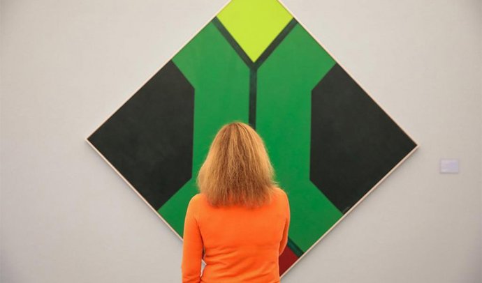 Una obra colorista de arte contemporáneo es observada por una mujer en el Bellas Artes de Granada.