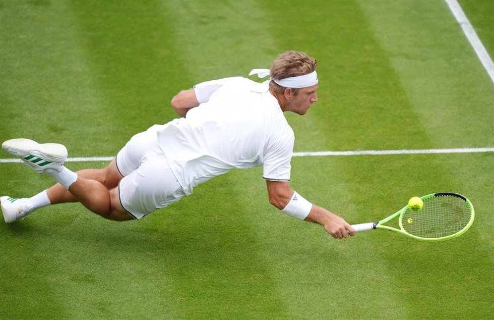 El tenista español Alejandro Davidovich Fokina cae al intentar devolver una bola del húngaro Fabian Marozsan durante su partido de segunda ronda individual masculina de Wimbledon