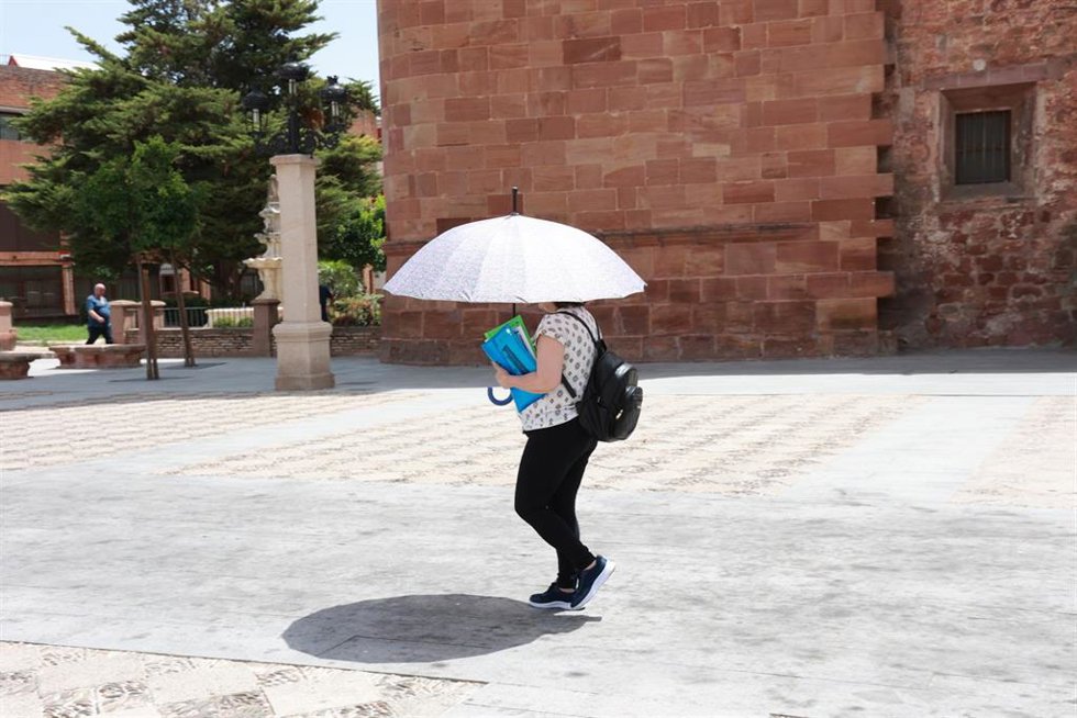Una mujer se protege del sol con un paraguas.