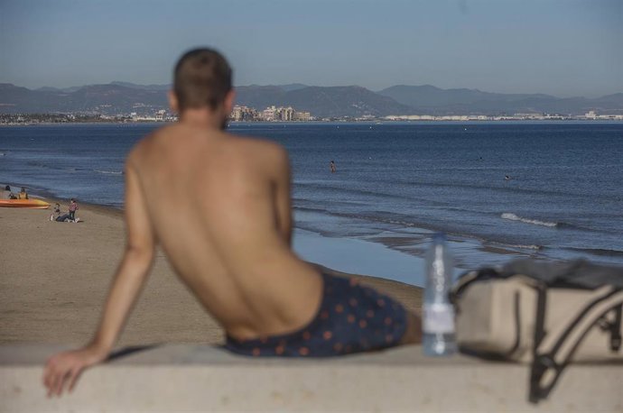 Archivo - Un chico en bañador toma el sol en la playa, en imagen de archivo. 