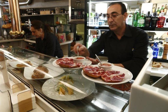 Archivo - Trabajadores de un bar sirven comida.