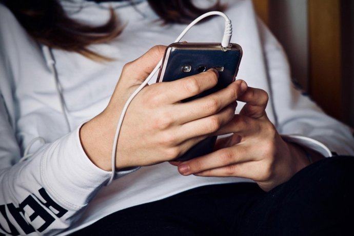 Una adolescente mira la pantalla de su teléfono móvil.