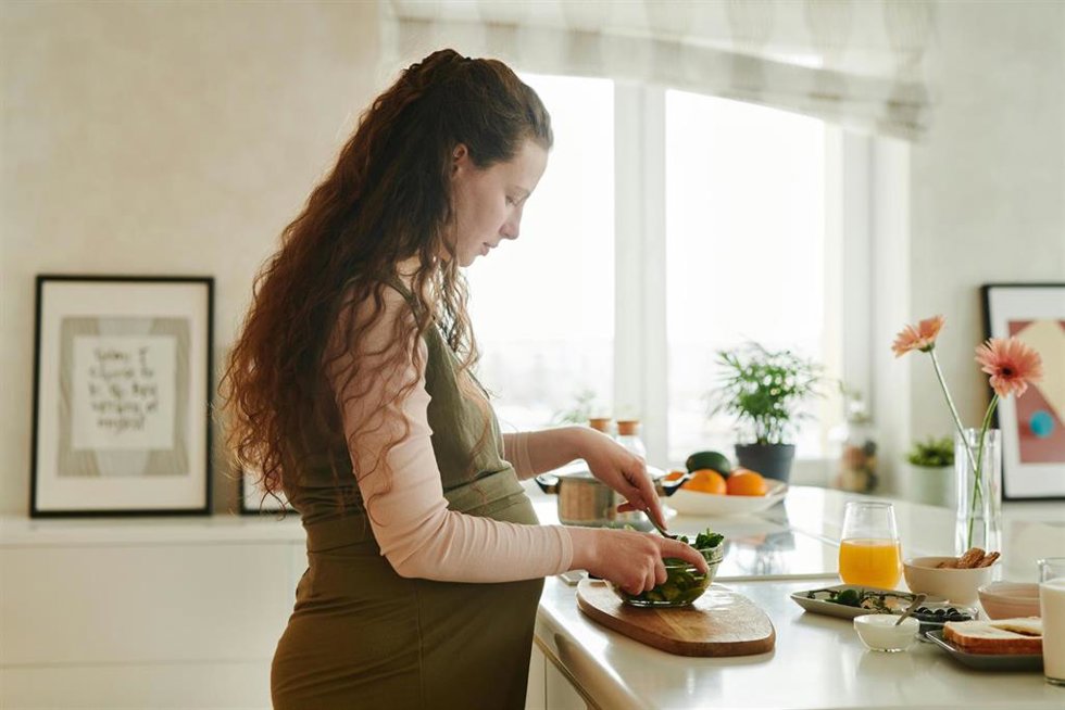Una mujer embarazada se prepara un plato para comer