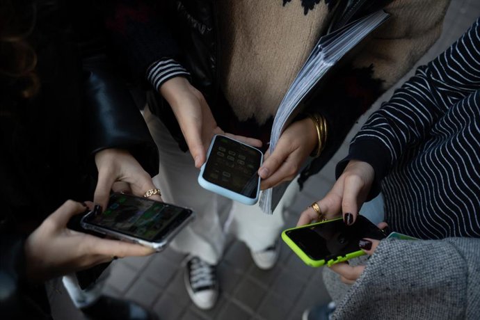 Archivo - Varias jóvenes usan el teléfono móvil.