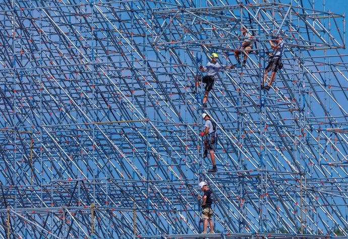 30 de junho de 2026, Mecklemburgo-Pomerânia Ocidental, Neustadt-Glewe: Montadores de andaimes estão montando um dos palcos principais no recinto do festival “Airbeat One”, no aeroporto. O maior festival de música eletrônica do norte da Alemanha acontecerá