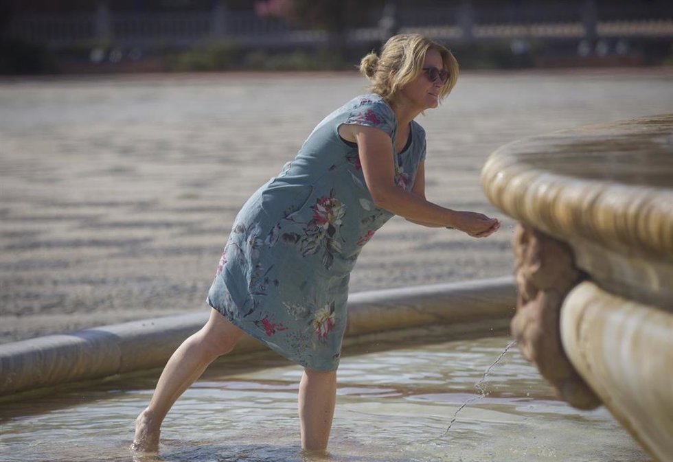 Archivo - Una mujer se refresca en la fuente de la Plaza de España durante el aviso naranja por calor activado por la Agencia Estatal de Meteorología (AEMET). Imagen de archivo.