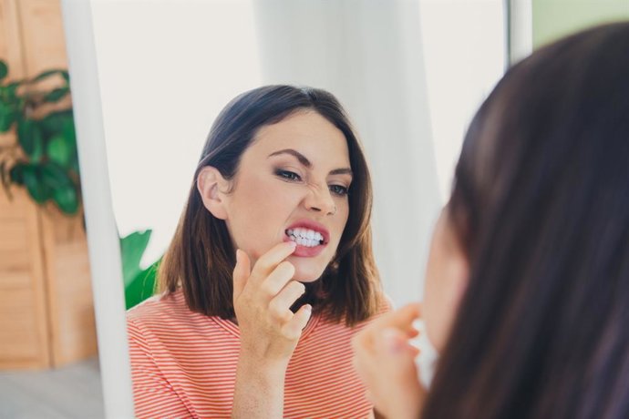 Archivo - Mujer mirando en el espejo el blanco de sus dientes.
