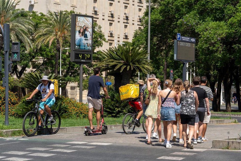 Archivo - Imágenes de personas al lado de un termómetro en las calles de la capital hispalense.