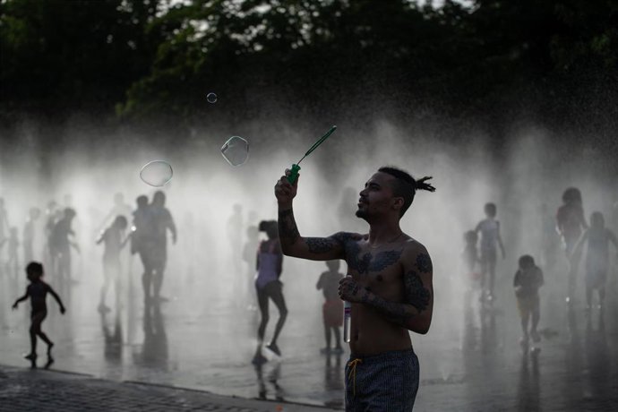 Varias personas se refrescan en una fuente.