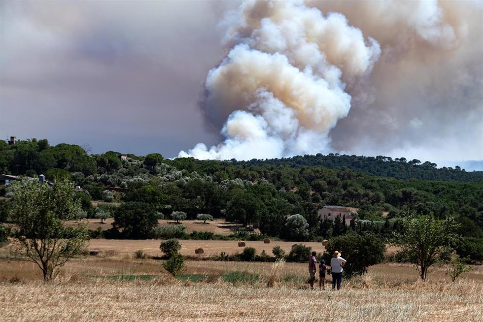 Varias personas observan el humo del incendio, en La Bisbal d'Empordà, Girona, Catalunya (España). Protecció Civil ha enviado una alerta de forma preventiva por la evolución del fuego, así como la presencia de humo y para evitar la movilidad en la zona ce