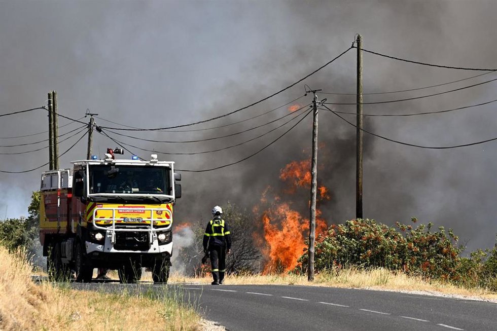 Un bombero de la Agencia de Protección Civil francesa camina por una carretera junto a un incendio forestal cerca de Ille-sur-Tet. El incendio se declaró el 4 de julio en una remota sierra cerca de Trevillach