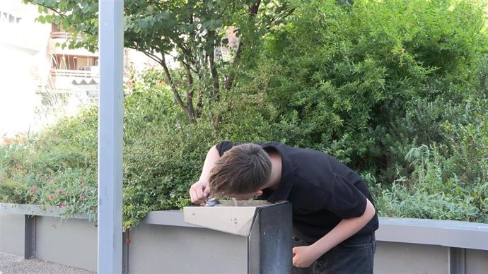 Un joven bebe agua de una fuente.