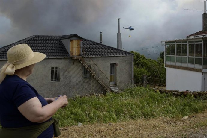 Vecina de Gabián observa las labores de extinción de un incendio forestal, a 14 de junio de 2026, en Boborás, Ourense, Galicia (España). La Consellería de Medio Rural de la Xunta de Galicia ha informado de un incendio forestal activo que se inició a las 2