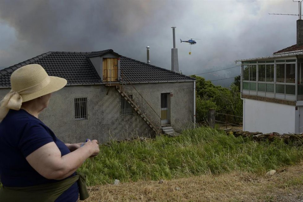 Vecina de Gabián observa las labores de extinción de un incendio forestal, a 14 de junio de 2026, en Boborás, Ourense, Galicia (España). La Consellería de Medio Rural de la Xunta de Galicia ha informado de un incendio forestal activo que se inició a las 2