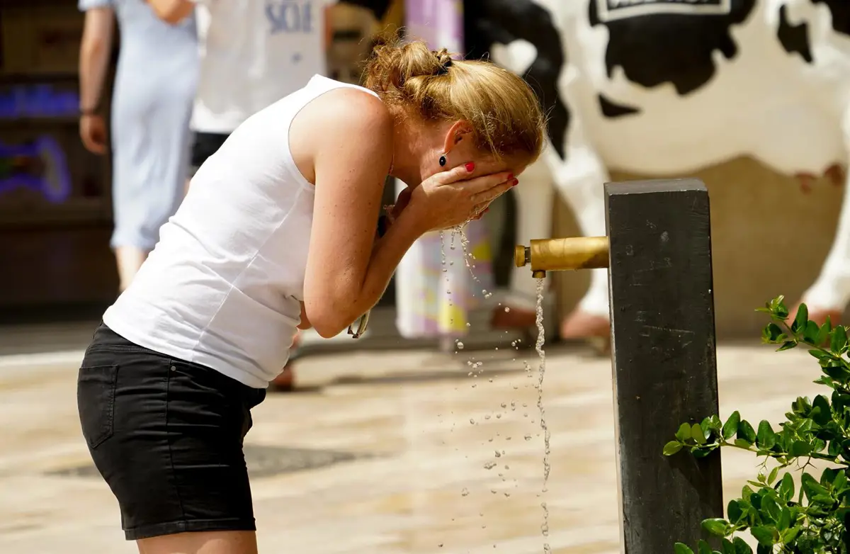 Mujer refrescándose en una fuente en Valencia
