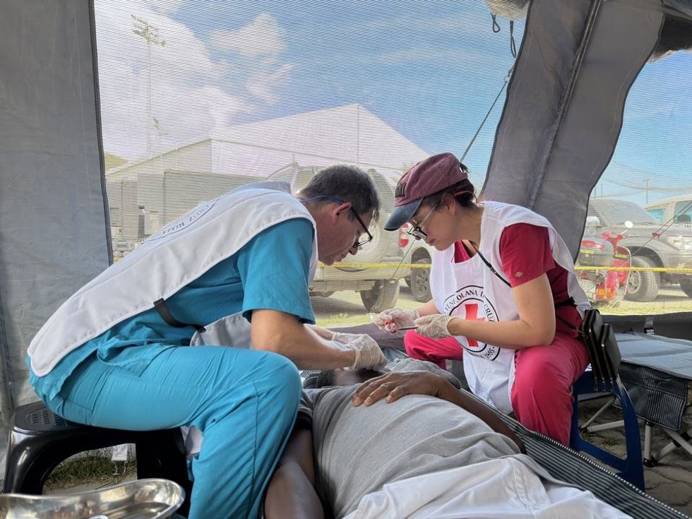 Dos sanitarios de Cruz Roja atienden a una persona.