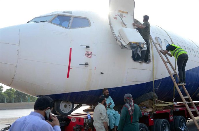 Archivo - Operarios del aeropuerto de Karachi (Pakistán) trabajan en el traslado de un Boeing 737 por carretera