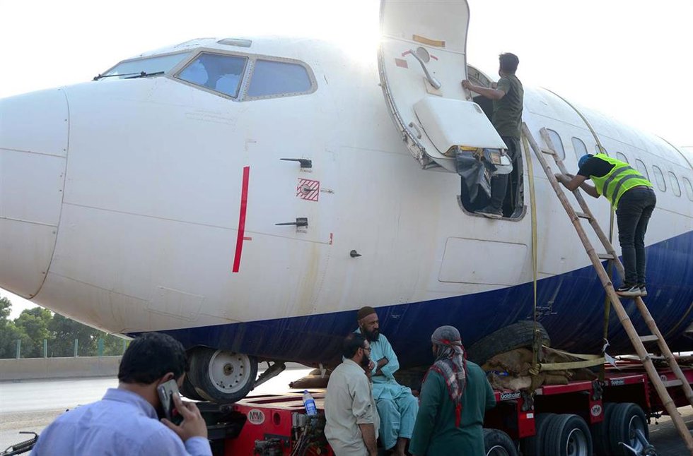 Archivo - Operarios del aeropuerto de Karachi (Pakistán) trabajan en el traslado de un Boeing 737 por carretera