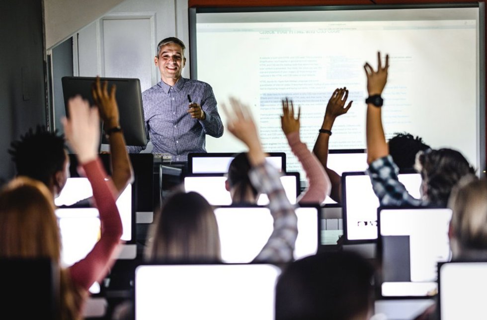 Profesor impartiendo clase en un aula universitaria.