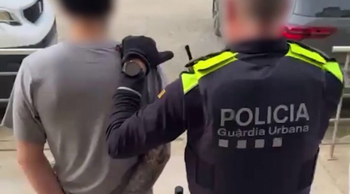 Un agent de la Guàrdia Urbana de Barcelona amb un dels 18 detinguts 