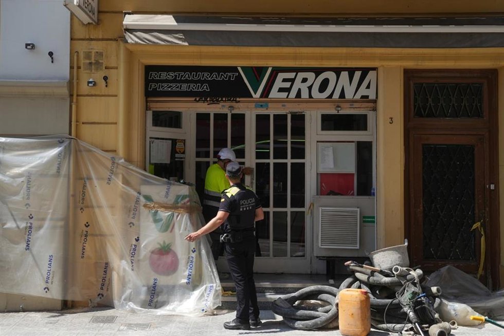 Un policía ante la pizzería Verona en el barrio del Putxet de Barcelona, lugar en el que se encuentra el socavón que ha provocado el desalojo de 8 fincas.