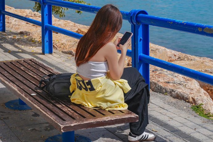 Joven usando su smartphone junto al mar en Alicante, España.