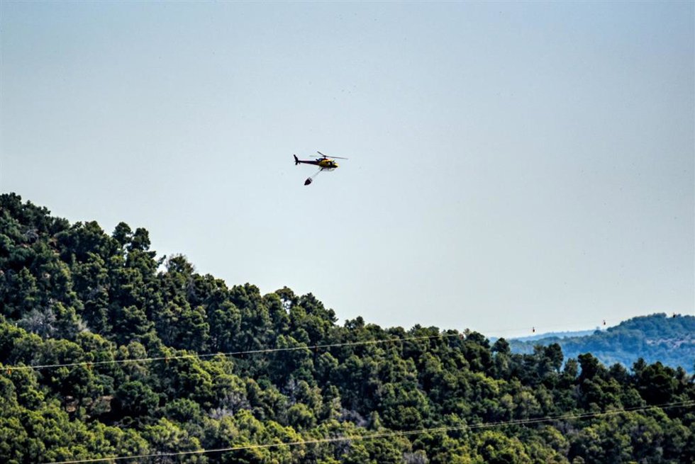 Un helicóptero de los bomberos sobrevuela terrenos quemados durante un incendio forestal en Sentmenat (Barcelona) este miércoles